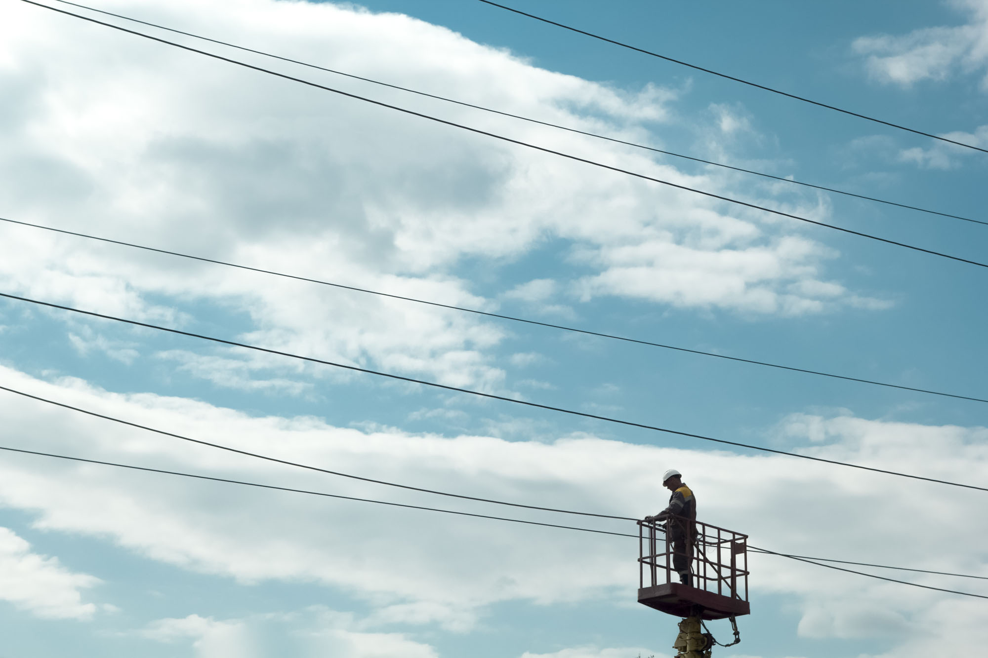 The electrician on the crane repairs high-voltage wires.